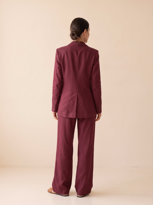Modelo de espaldas con el conjunto de blazer y pantalón efecto lino burdeos de NEVAIA