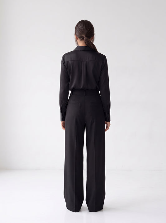 Modelo con el pantalón plisado negro de cintura alta de NEVAIA, vista de espalda