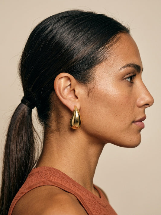 Modelo con los pendientes de gota dorados de NEVAIA, vista de perfil