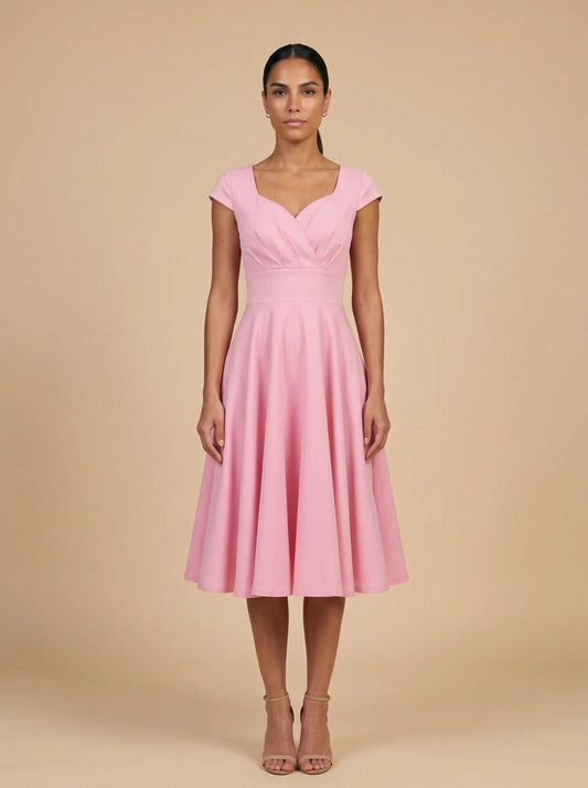 Modelo con el vestido vintage de vuelo rosa de NEVAIA, vista frontal: escote corazón con pliegues, manga casquillo y falda de vuelo
